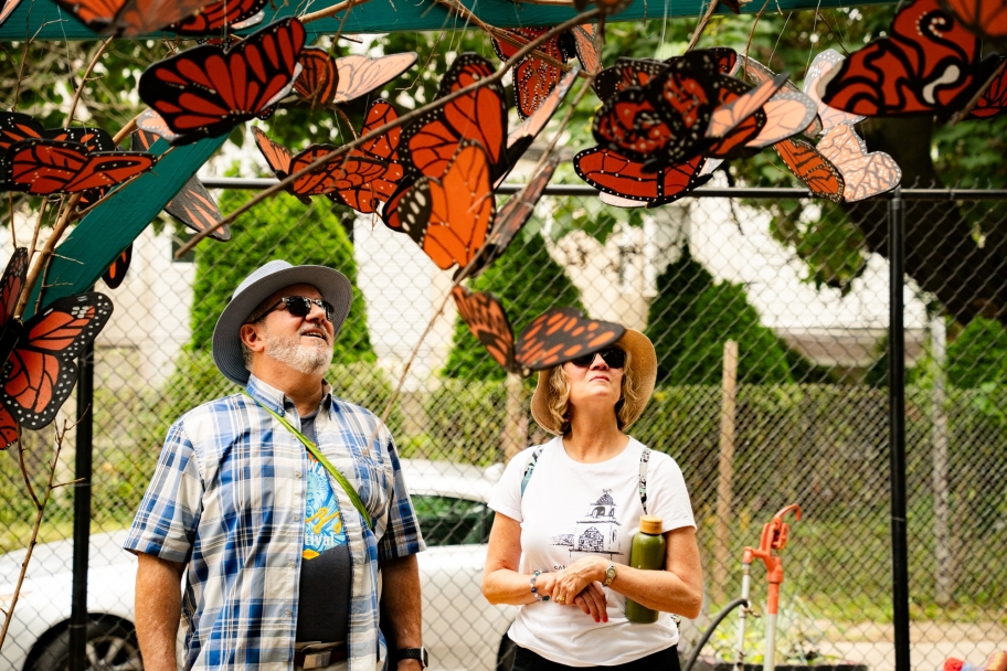 people standing under and admiring a butterfly installation at the gardens