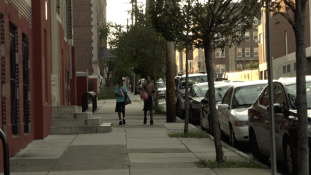 Two boys walk down a sidewalk in a residential neighborhood in Philadelphia