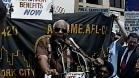 A man speaking at a rally for unemployment benefits