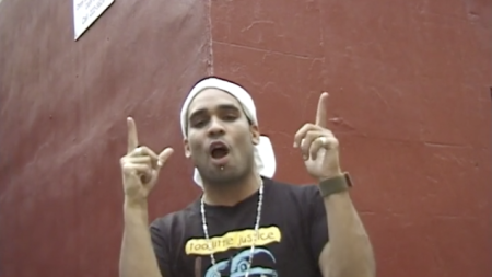 man with a shirt that says 'too little justice' and pointing fingers up